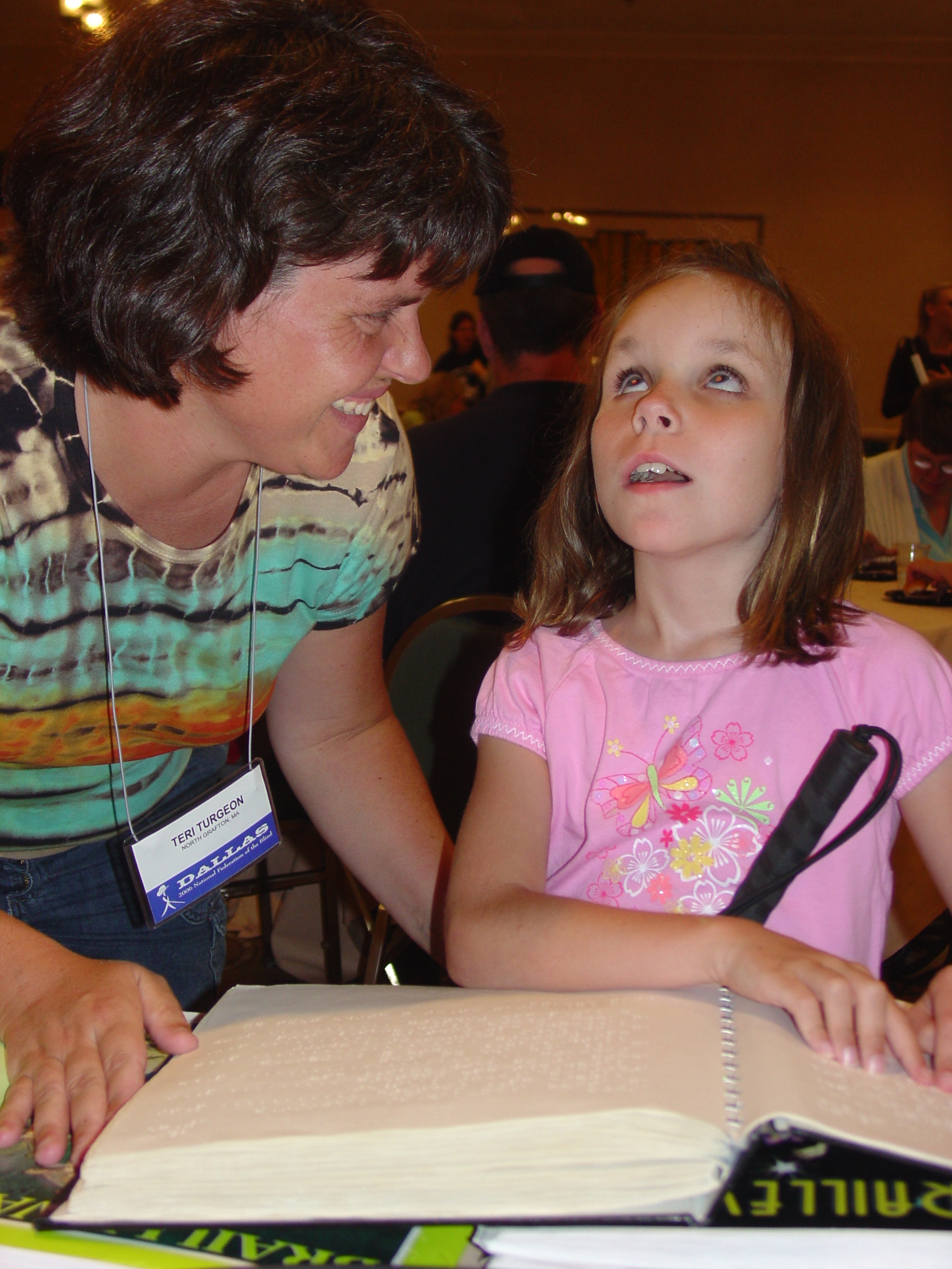 Child reading Braille as mother looks on